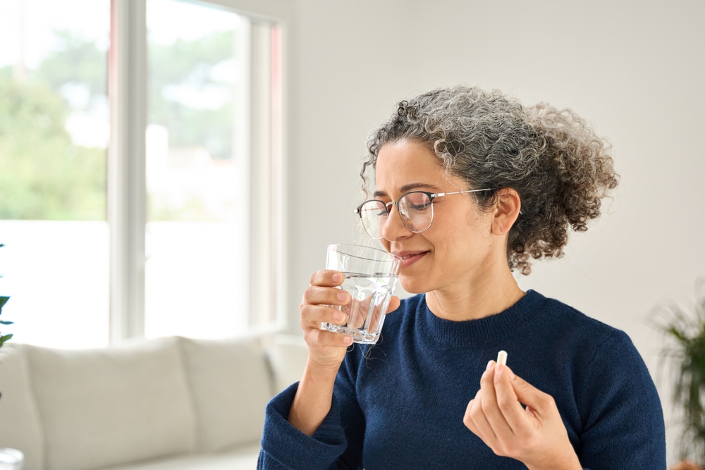 Happy,healthy,woman,of,middle,age,talking,pill,holding,glass