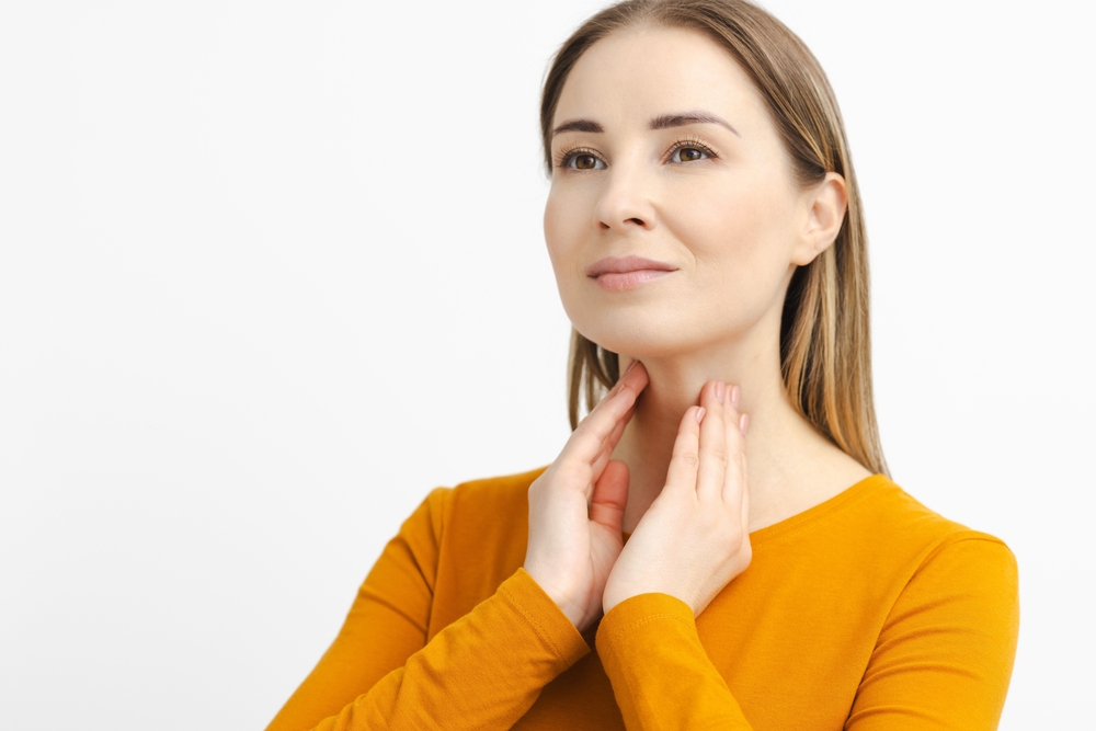 Woman,self,touching,her,neck,to,check,the,thyroid,gland.