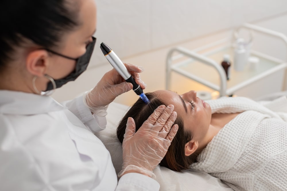 Caucasian,girl,undergoes,scalp,treatment,to,stimulate,hair,regrowth,using