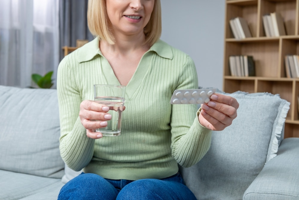 Blonde,woman,in,her,50s,taking,hormone,replacement,pills