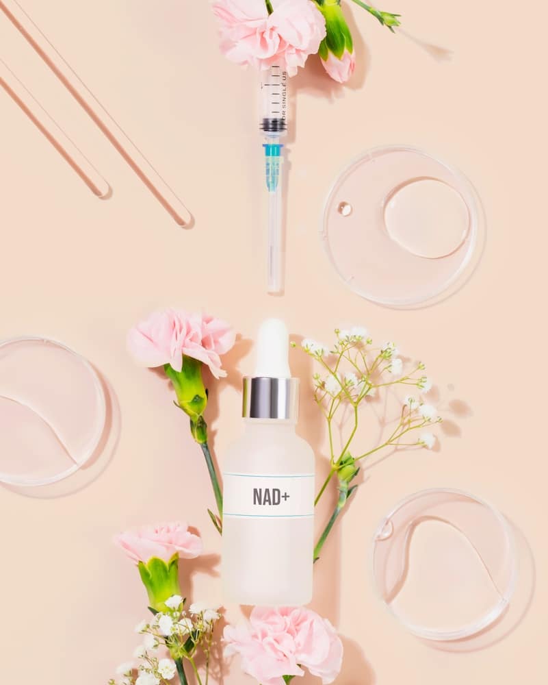 Nad,skincare,bottle,with,syringe,,lab,tools,,and,delicate,flowers