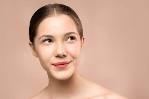 pexels-photo-3762761-3762761-1 Portrait of a young woman smiling with radiant, flawless skin against a nude background.