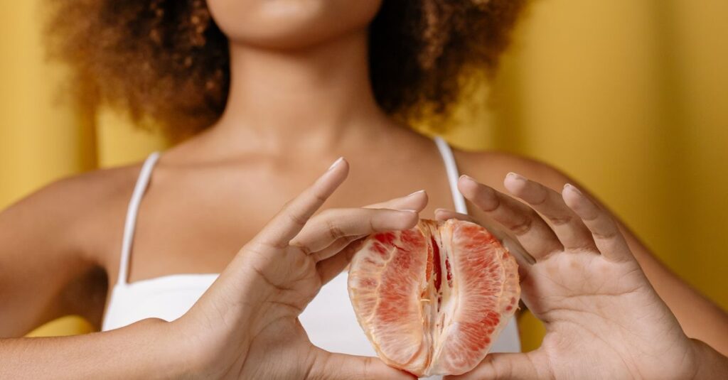 pexels-photo-5901023-5901023 A woman in a white top holding a grapefruit, focused on healthy lifestyle.